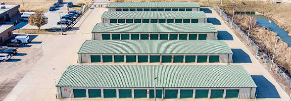 A large green building complex with a parking lot in front.