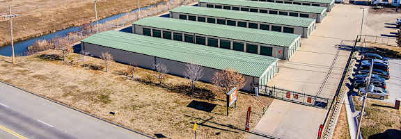 A large green building is surrounded by a parking lot and other industrial buildings.