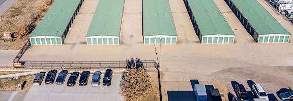 A parking lot with a green roofed building in the background.