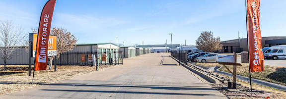 A storage facility with orange flags on either side of the driveway.