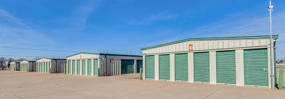 A storage facility with green doors and a clear blue sky.