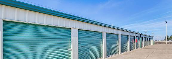 A long row of storage units with closed green doors.