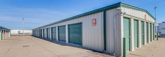 A long storage unit building with green trim and doors.