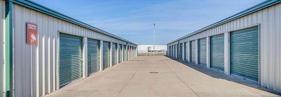 A long row of storage units with closed doors and a red sign on the wall.