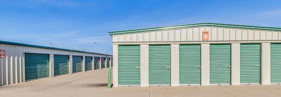A storage facility with green doors and a white building.