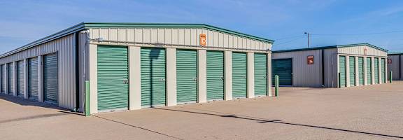 A storage facility with green doors and a clear blue sky.