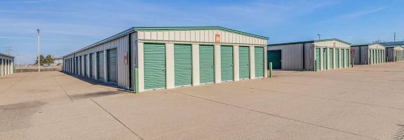A storage facility with multiple units and green doors.