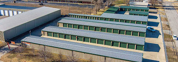 A large industrial building with a green roof is surrounded by a parking lot.