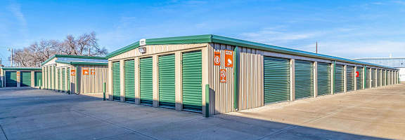 A storage facility with green and brown units under a clear blue sky.