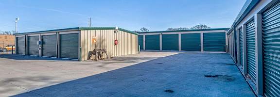 A row of storage units with closed doors and a bicycle in front of the first one.