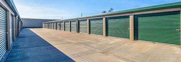 A long row of green storage units with closed doors.