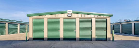 A storage facility with green doors and a white sign on top.