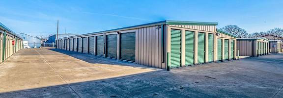 A storage facility with green doors and a clear blue sky.
