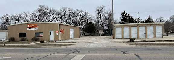 A building with a red sign that says "DENNIS TOMAS" sits next to a smaller building with a white sign.