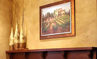 A painting of a street scene is hanging on a wall above a wooden shelf.