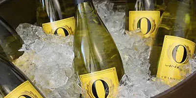 A bottle of champagne with a yellow label is surrounded by ice.