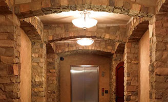 A stone archway leads to a door in a stone wall.