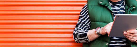 a man sitting on a orange wall using a laptop computer
