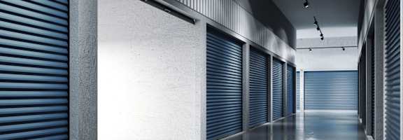 A long hallway with blue doors and a concrete floor.