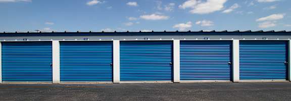 A row of blue storage units with a clear blue sky above.
