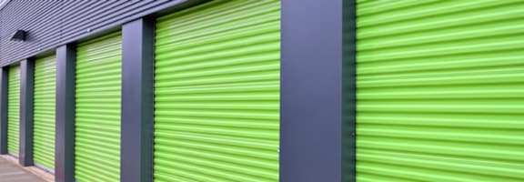 A series of green storage units with grey pillars and a grey roof.