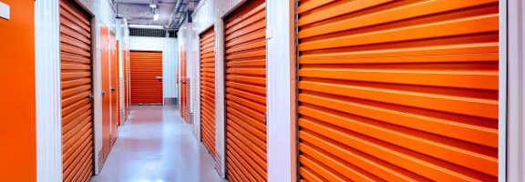 A long hallway with orange doors in a storage facility.