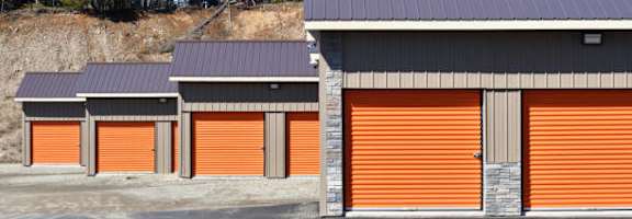 A storage facility with orange doors and a grey roof.