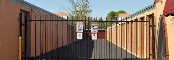 A black gate with a yellow post and a sign on it.