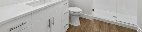 A white bathroom with a sink, toilet, and shower.