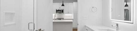 A white bathroom with a sink, mirror, and a door.