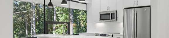 A modern kitchen with a white countertop and stainless steel appliances.