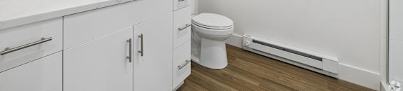 A white bathroom with a sink, toilet, and mirror.