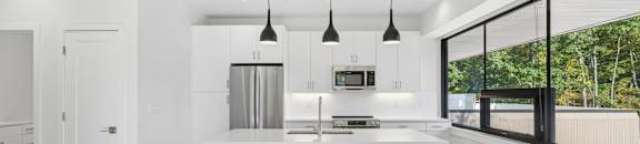 A modern kitchen with a white island and pendant lights.