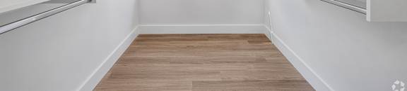 A long, narrow hallway with white walls and wood flooring.