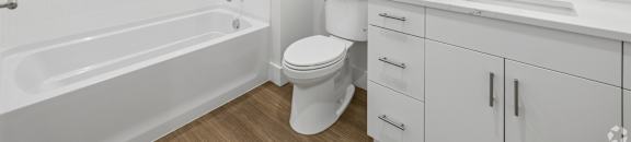 A white bathroom with a tub, toilet, sink, and mirror.