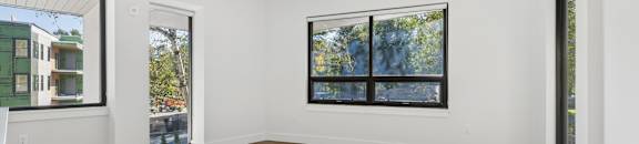 A room with a large rug on the floor and a window with a view of trees.