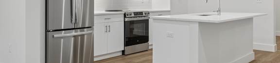 A modern kitchen with white cabinets and stainless steel appliances.