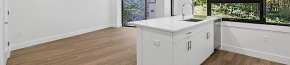 A kitchen with white cabinets and a wooden floor.