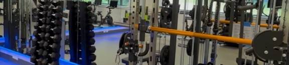 A gym with a variety of equipment including weights and benches.
