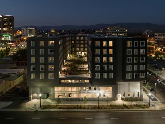 A modern building with a lot of windows is lit up at night.