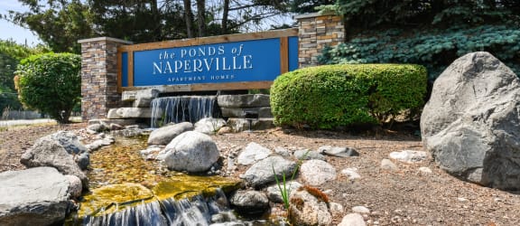 a waterfall in front of a sign for the ponds of naperville