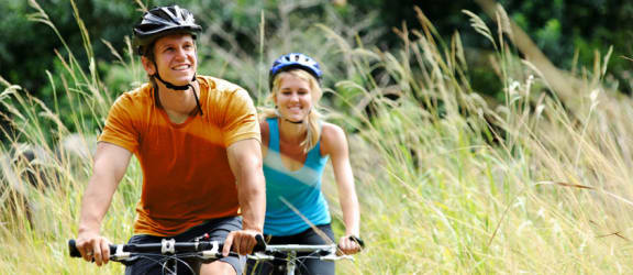 a man and a woman riding bikes through a field