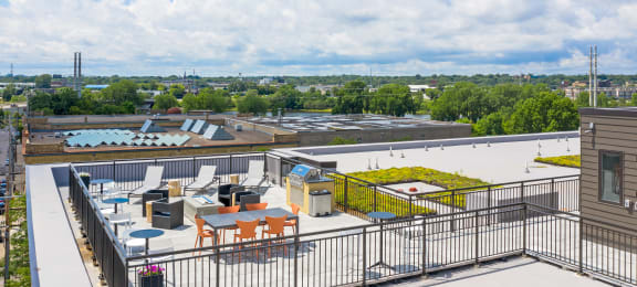 a rooftop patio with tables and chairs and a pool with trees in the background