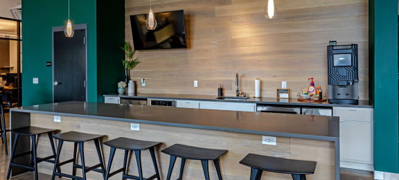 a bar with stools and a coffee machine in a room with green walls