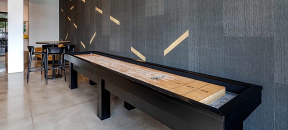 a shuffleboard table sits in the middle of a room with tables and chairs in the background