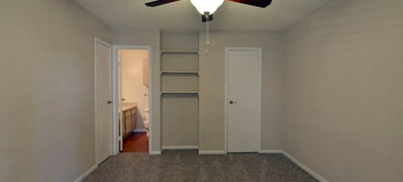 Model home bedroom with built in shelving, bathroom access, and door