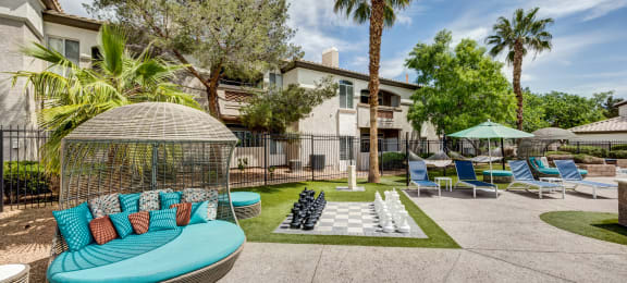an outdoor lounge area with a gazebo, lounge chairs and giant chess set