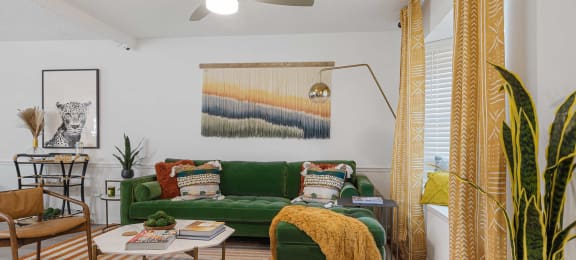 a living room with a green couch and yellow curtains