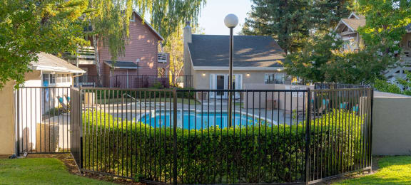 a swimming pool behind a wrought iron fence in a backyard