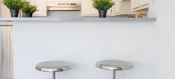 a kitchen with three bar stools in front of a counter